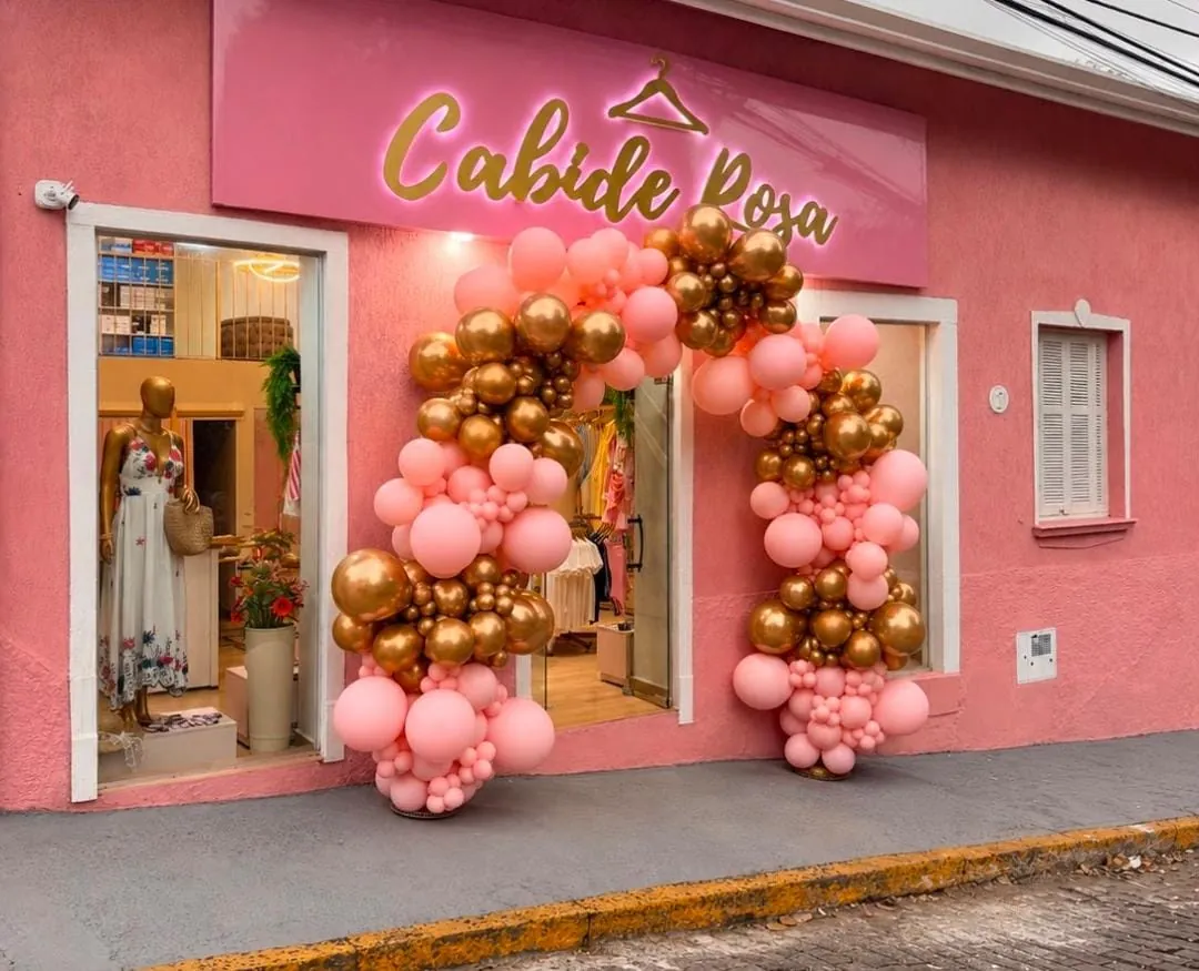 Fachada da loja Cabide Rosa com letras douradas iluminadas