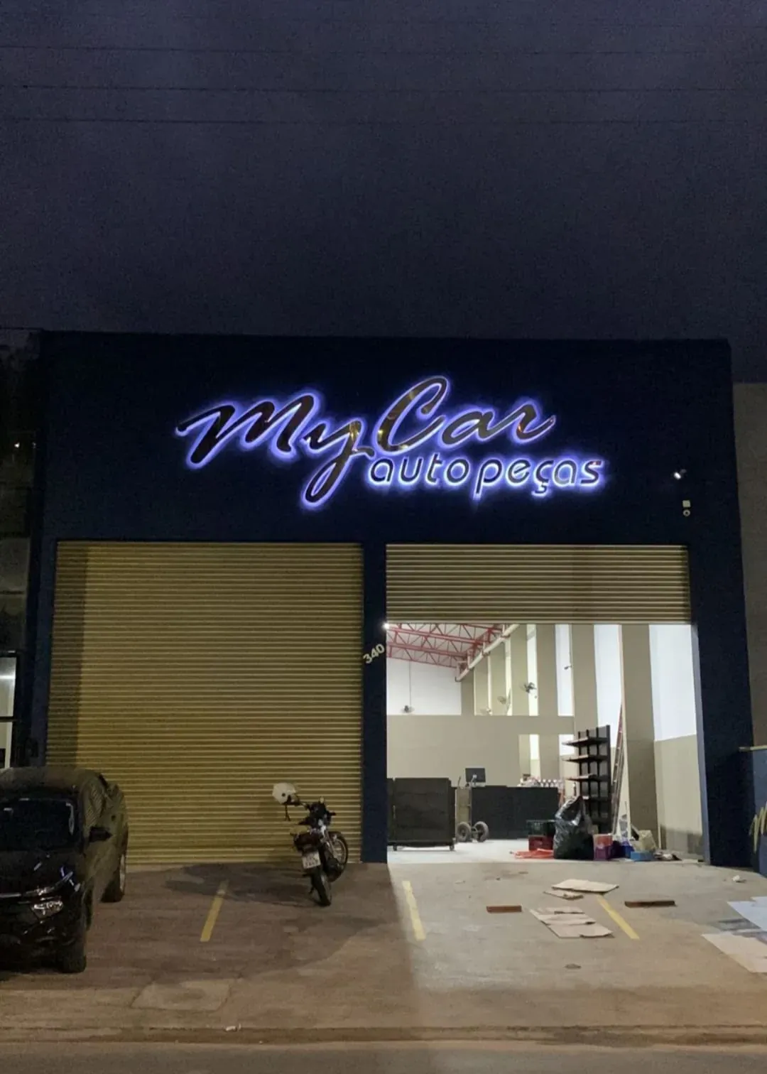 Fachada da MyCar Autopeças com letras em relevo iluminadas à noite